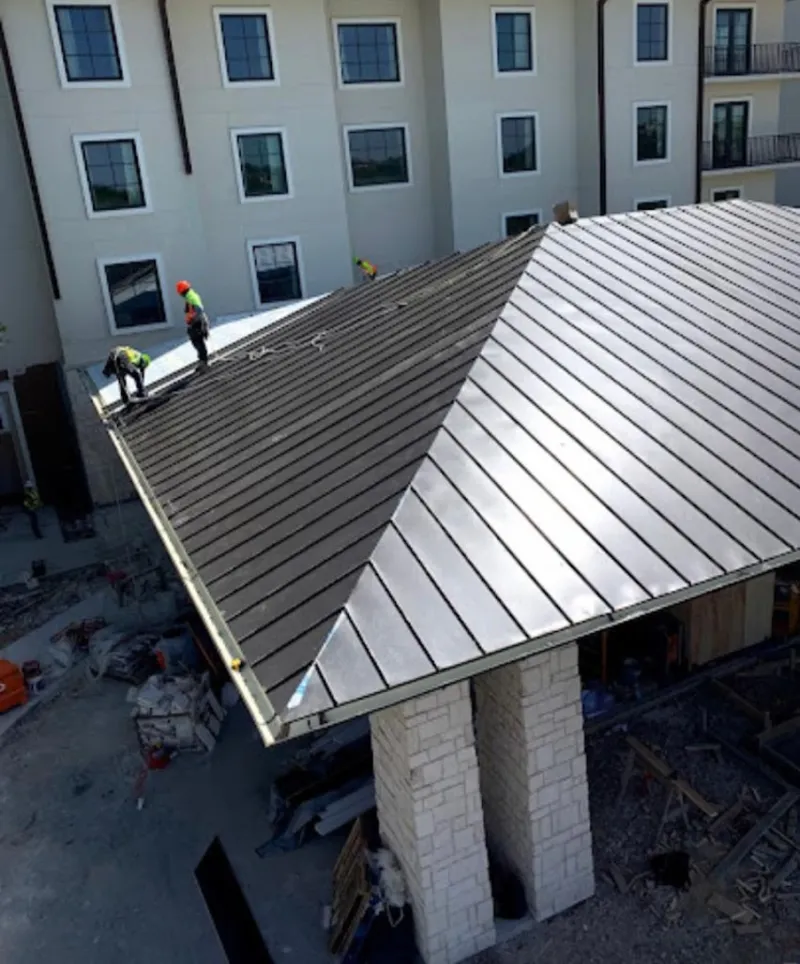Crew installing standing seam metal roof panels on a commercial project in Randolph